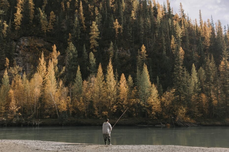 An angler holds a multi-piece travel spinning rod in a scenic outdoor setting, emphasizing portable fishing gear for adventure travel.