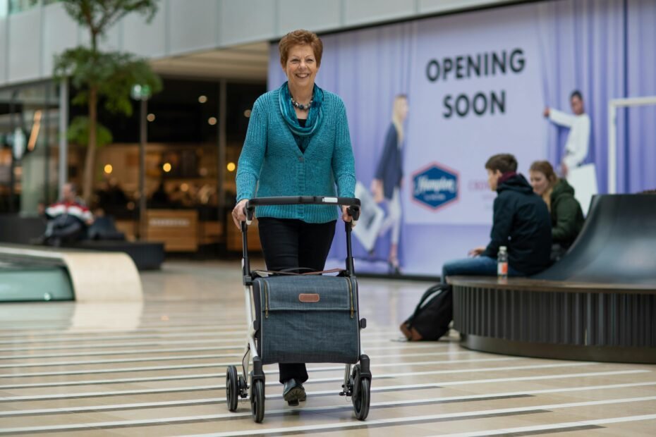 A smiling senior person using a modern, lightweight, foldable travel walker to move confidently through a bright airport terminal, symbolizing independence and active travel.