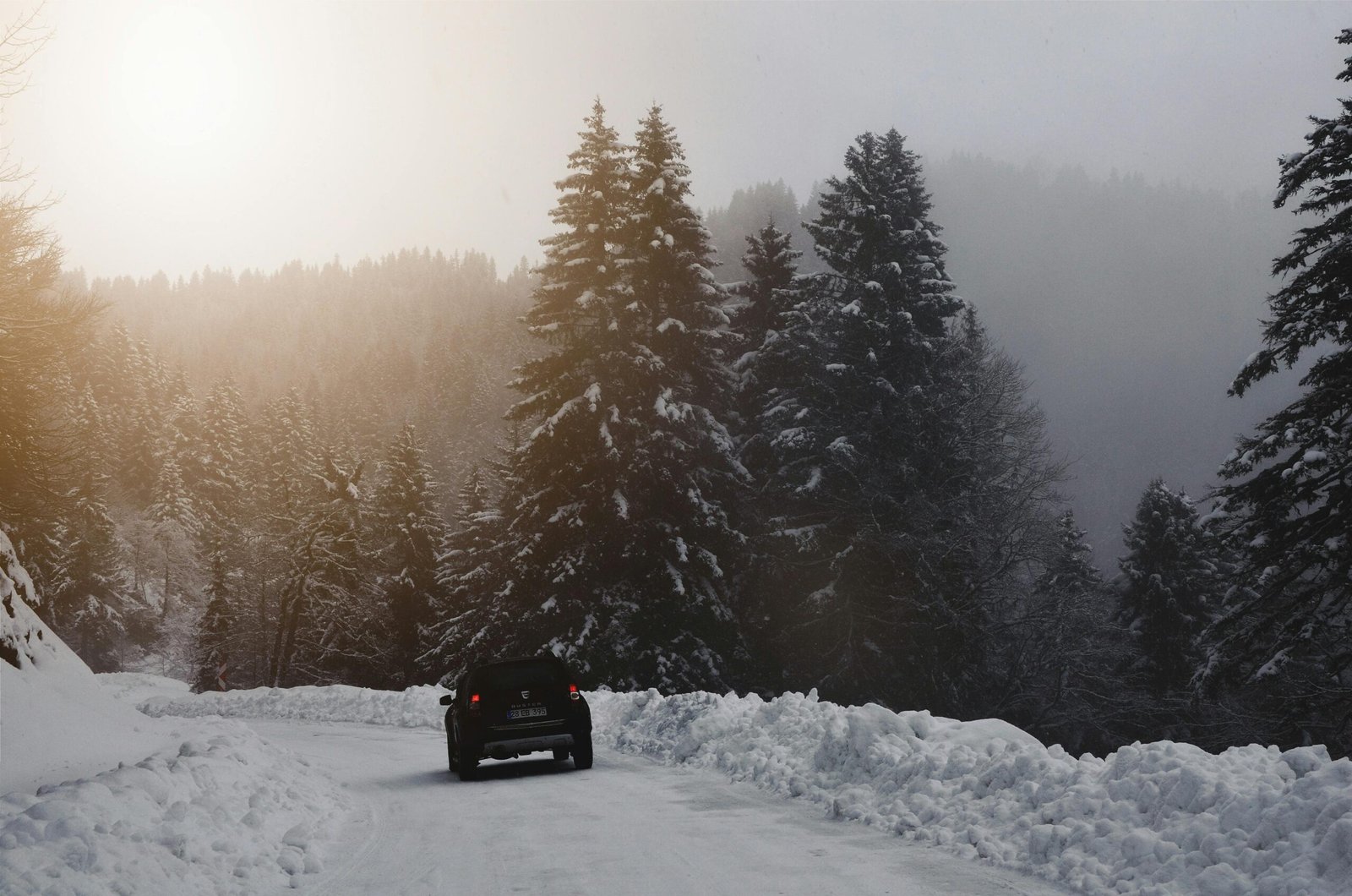 Car driving on a snow-covered road in Greater Cincinnati during a winter travel advisory, illustrating safe driving and preparedness for snow emergency levels.