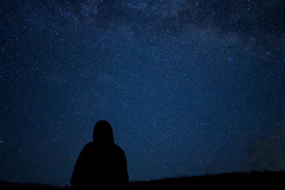 Star traveler meditating under a starry night sky, symbolizing cosmic origins, spiritual connection, and life purpose on Earth.