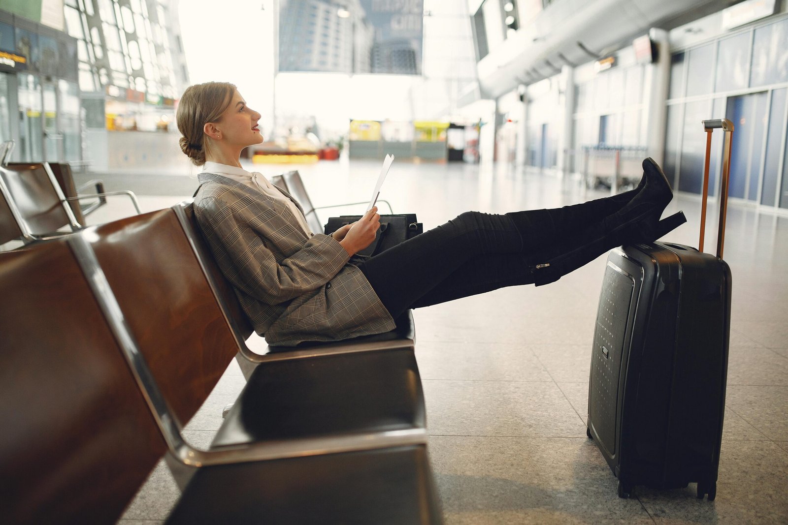 Stylish woman comfortably wearing black Chico's Travelers pants in an airport, highlighting their wrinkle-resistant fabric and elegant design for effortless travel.