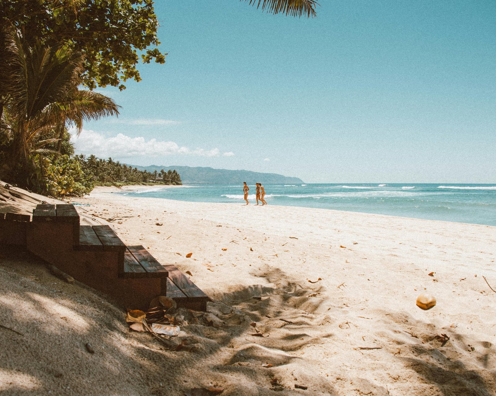 Happy couple enjoying a luxurious Hawaiian beach vacation with Aloha Travel, featuring pristine turquoise waters and palm trees.