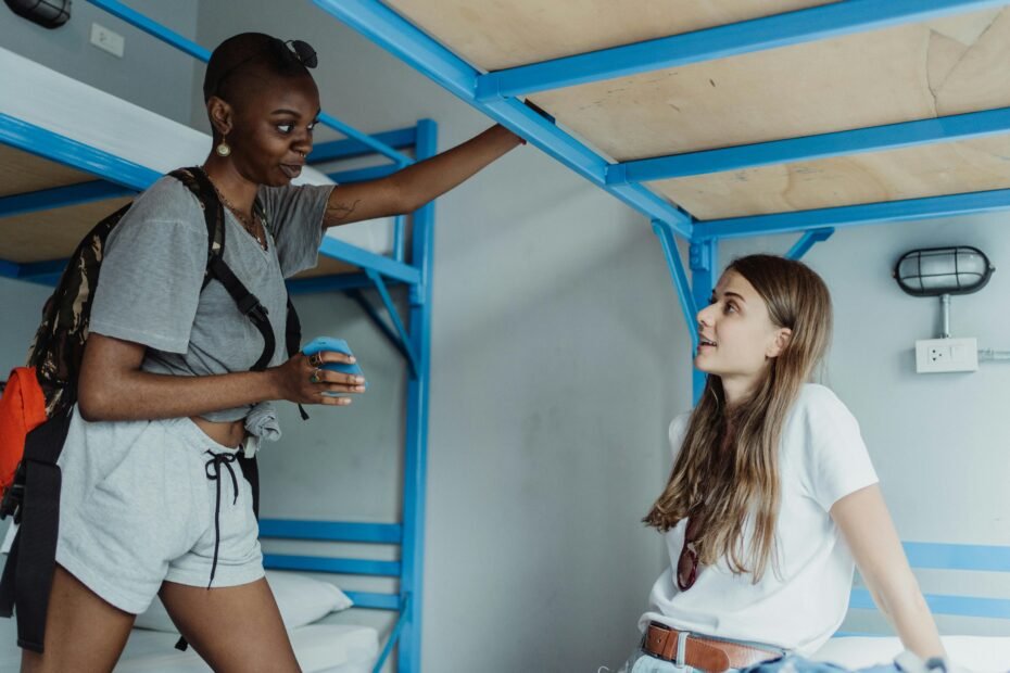 Diverse young travelers laughing and connecting in a hostel, illustrating shared travel experiences and building community while overcoming solo travel loneliness abroad.