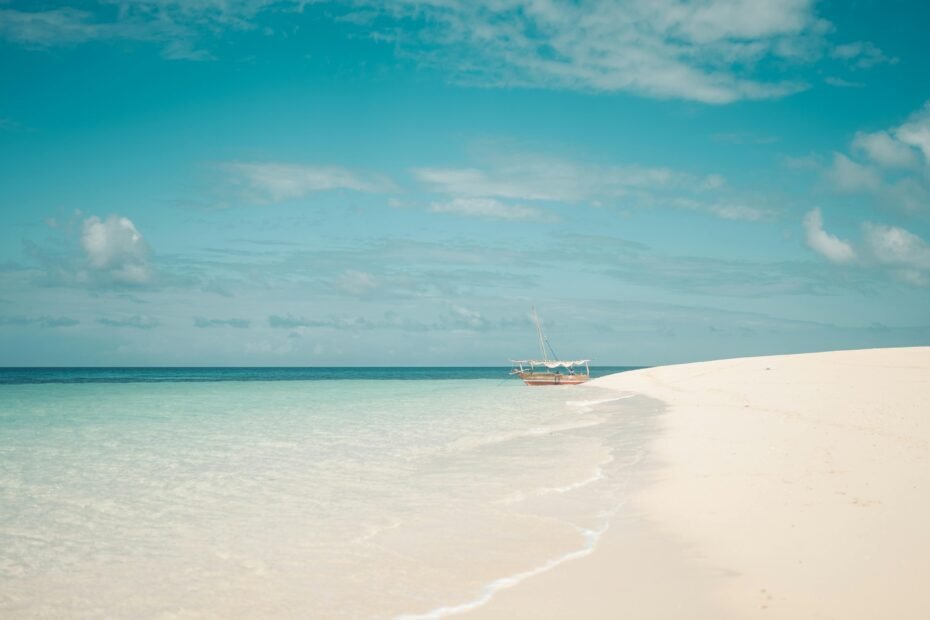 Traditional dhow boat on a pristine Zanzibar beach with turquoise water at sunset, representing a dream travel adventure blending culture, history, and relaxation.