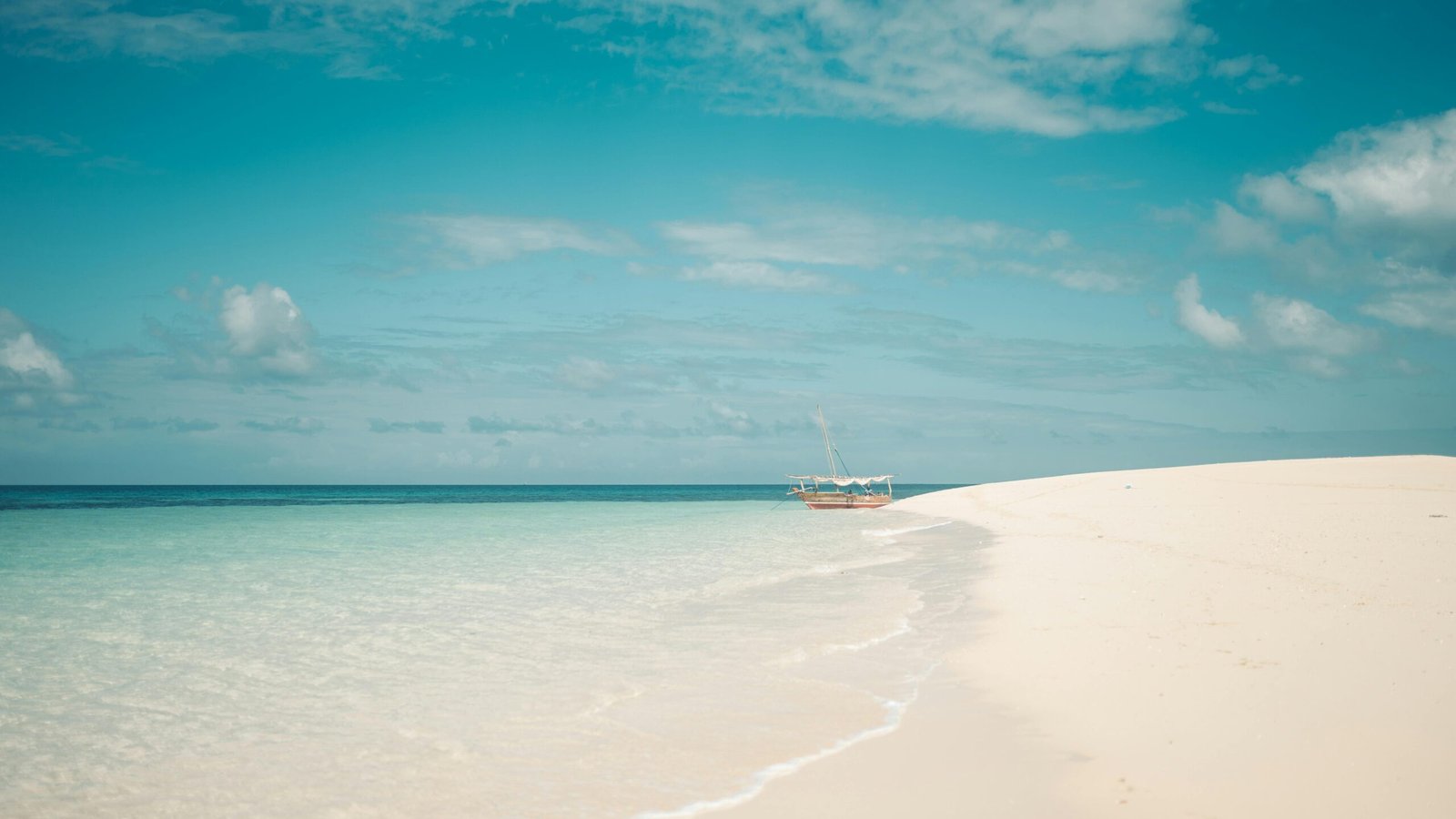 Traditional dhow boat on a pristine Zanzibar beach with turquoise water at sunset, representing a dream travel adventure blending culture, history, and relaxation.