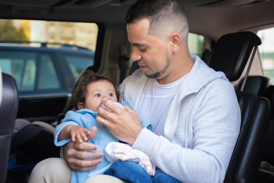 Parents gently looking at their newborn baby in a rear-facing car seat during a family car trip, illustrating safe car travel with infants.