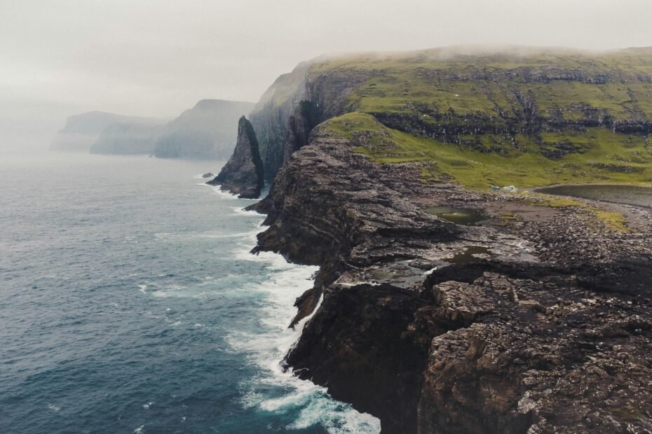 Faroe Islands dramatic green cliffs plunging into the wild Atlantic Ocean, showcasing the archipelago's untouched natural beauty and mythical landscapes.
