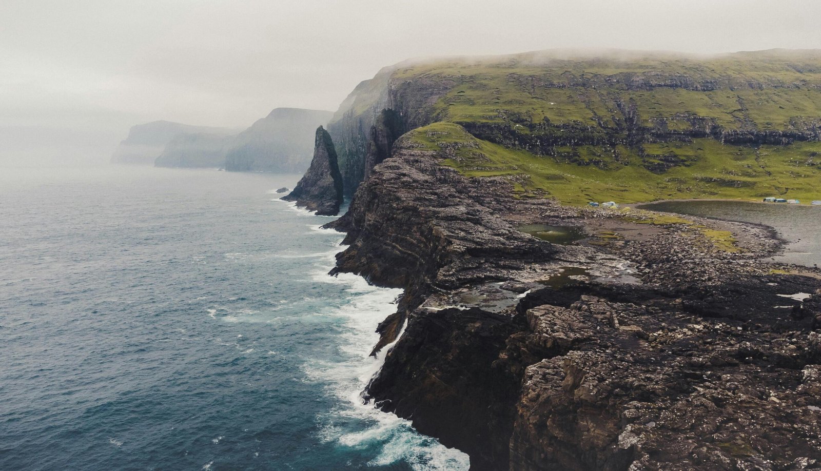 Faroe Islands dramatic green cliffs plunging into the wild Atlantic Ocean, showcasing the archipelago's untouched natural beauty and mythical landscapes.