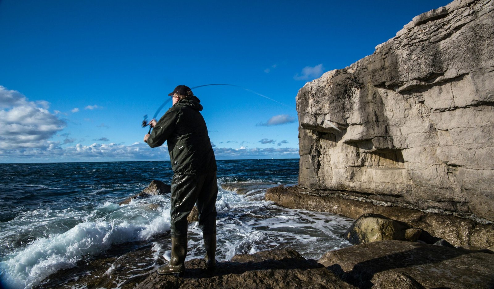 An angler on a scenic travel destination, holding a compact multi-piece traveling fishing rod, ready for a portable fishing adventure.